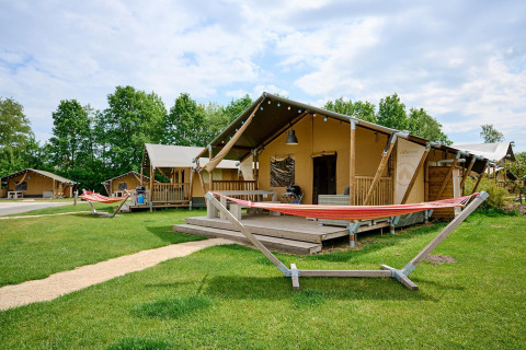 Safari-teltet Villatent Nomad med veranda og hængekøje på Vakantiepark Sallandshoeve i Holland, omgivet af grønne træer.