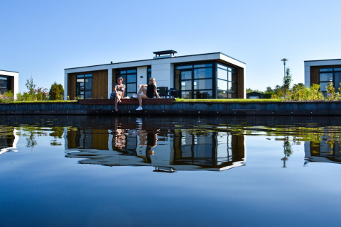 Dos personas se relajan junto al agua en Villa Nautica Deluxe, MarinaPark Residentie Nieuw Loosdrecht, Países Bajos.