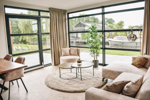 Salón moderno y luminoso en Villa Nautica Deluxe, con ventanales y vistas al canal en MarinaPark Nieuw Loosdrecht.