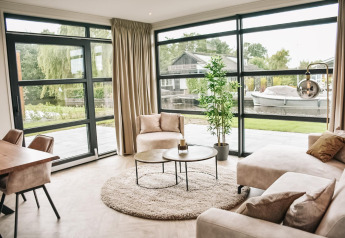 Salón moderno y luminoso en Villa Nautica Deluxe, con ventanales y vistas al canal en MarinaPark Nieuw Loosdrecht.