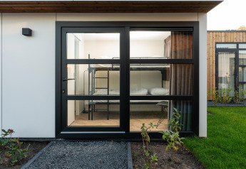 Udsigt til moderne indkvartering med køjesenge gennem store glasdøre ved Villa Nautica Deluxe i Holland.