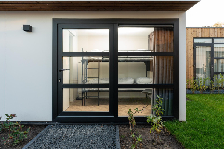 Vue à travers de grandes portes vitrées sur des lits superposés à la Villa Nautica Deluxe aux Pays-Bas.