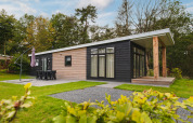 Luksuriøs lodge med sauna ved Vakantiepark Hölte i Holland, omgivet af grønt og moderne arkitektur.
