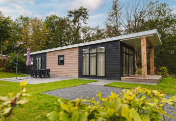 Luksuriøs lodge med sauna ved Vakantiepark Hölte i Holland, omgivet af grønt og moderne arkitektur.