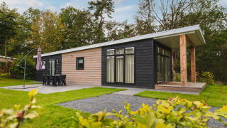 Luxe lodge met sauna bij Vakantiepark Hölte in Nederland, moderne bouwstijl en groene omgeving.