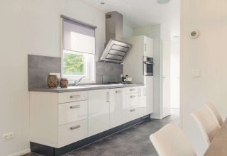 Cucina moderna in una lodge di lusso con sauna al Vakantiepark Hölte, Paesi Bassi, con mobili bianchi.