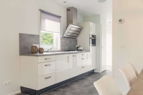 Cucina moderna in una lodge di lusso con sauna al Vakantiepark Hölte, Paesi Bassi, con mobili bianchi.