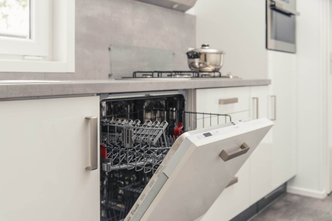 Modern dishwasher with open door in a luxury lodge kitchen with sauna at Vakantiepark Hölte, Netherlands.