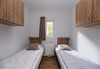 Moderne lodgeværelse med to enkeltsenge, træskabe og vindue på Vakantiepark Hölte, Nederlandene.