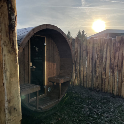 Sauna rotonda in legno al tramonto nell’area esterna di un luxury lodge a Vakantiepark Hölte, Paesi Bassi.
