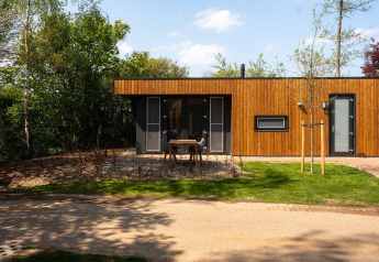 Modern wooden Oak Lodge at Vakantiepark Hölte in the Netherlands, with patio and surrounding trees.