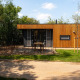 Moderne træhytte kaldet Oak Lodge ved Vakantiepark Hölte, Holland, omgivet af grøn have og træer.