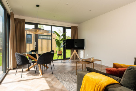 Soggiorno moderno alla Oak Lodge di Vakantiepark Hölte, Paesi Bassi, con ampie vetrate e arredo accogliente.