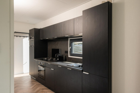 Cucina moderna con mobili scuri e finestra nell’Oak Lodge presso Vakantiepark Hölte, Paesi Bassi.