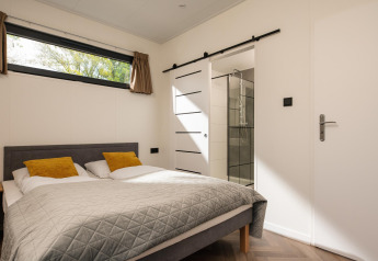 Dormitorio en Oak Lodge, Vakantiepark Hölte, Países Bajos, con cama doble y baño moderno en suite.