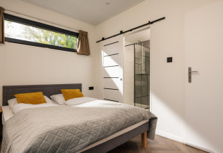 Dormitorio en Oak Lodge, Vakantiepark Hölte, Países Bajos, con cama doble y baño moderno en suite.