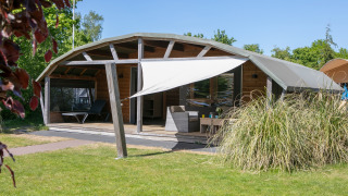 Casa de campo en Holiday Park 't Rheezerwold, Países Bajos, con terraza y toldo vistos desde el exterior.