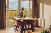 Lys stue i Tiny cabin på Vakantiepark Hölte, Holland, med store vinduer og moderne spisebord.