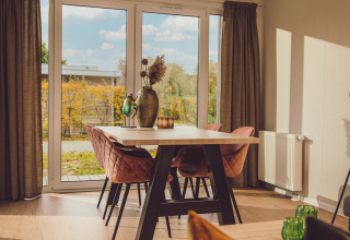 Soggiorno luminoso in una tiny cabin al Vakantiepark Hölte, Paesi Bassi, con ampie finestre e arredo moderno.