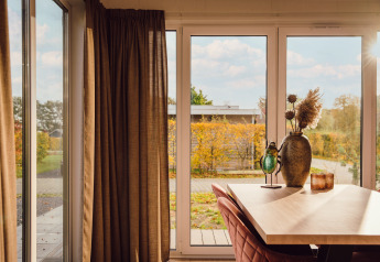 Sonnenlicht fällt in ein Tiny House namens Tiny cabin im Vakantiepark Hölte, Niederlande, mit Gartenblick.