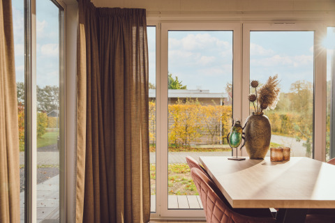 Zonnestralen in de Tiny cabin op Vakantiepark Hölte, Nederland, met tuinzicht en warme decoratie.