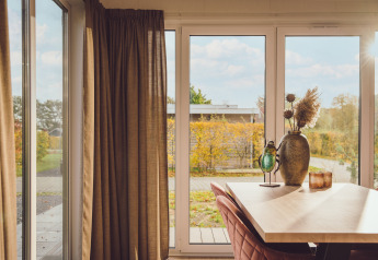 Zonnestralen in de Tiny cabin op Vakantiepark Hölte, Nederland, met tuinzicht en warme decoratie.