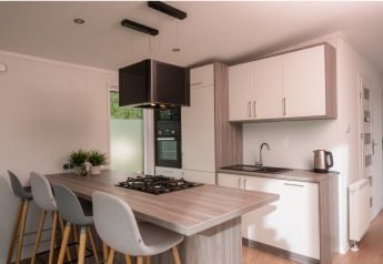 Moderne compacte keuken in een tiny cabin op Vakantiepark Hölte, Nederland, met kookeiland en stoelen.