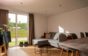 Salon lumineux et moderne d'une tiny house au Vakantiepark Hölte, Pays-Bas, avec vue sur le jardin.