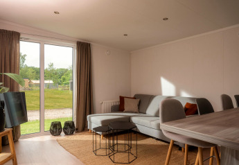 Lichte, moderne woonkamer in een tiny cabin bij Vakantiepark Hölte, Nederland, met uitzicht op de tuin.