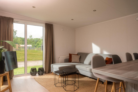 Helles, modernes Wohnzimmer in einem Tiny House im Vakantiepark Hölte, Niederlande, mit Gartenblick.