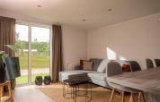 Lys og moderne stue i en tiny house ved Vakantiepark Hölte i Nederlandene med udsigt til haven.