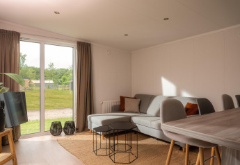 Helles, modernes Wohnzimmer in einem Tiny House im Vakantiepark Hölte, Niederlande, mit Gartenblick.