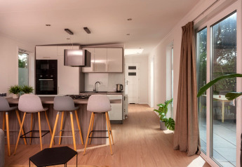 Cuisine moderne dans une tiny house avec tabourets, parquet, grandes fenêtres et terrasse aux Pays-Bas.
