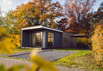 Modernes Tiny House Tiny Cabin mit Whirlpool, umgeben von Herbstbäumen im Vakantiepark Hölte, Niederlande.