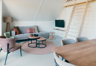 Salón contemporáneo en Big Lodge del Holiday Park De Boshoek, Países Bajos, con altillo y muebles modernos.