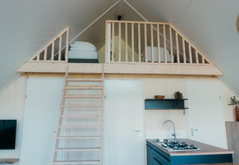 Intérieur du Big lodge au Holiday park De Boshoek aux Pays-Bas avec mezzanine, lits, cuisine et échelle.