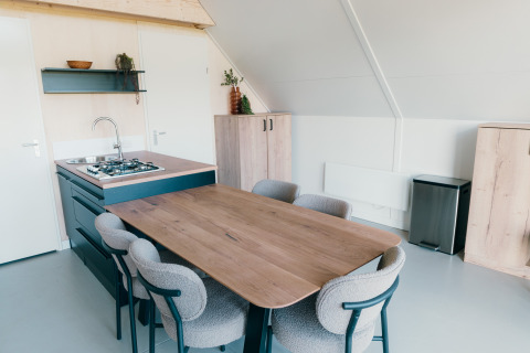 Moderne spiseplads og tekøkken i Big lodge på Holiday park De Boshoek, Nederlandene, med seks stole.