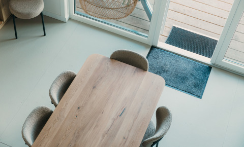 Zicht op een moderne eettafel met vier stoelen bij grote ramen in Big lodge, De Boshoek, Nederland.