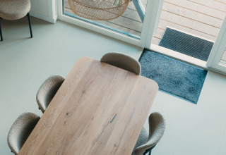 Uitzicht op een moderne eettafel met vier stoelen bij grote ramen in Big lodge, De Boshoek, Nederland.