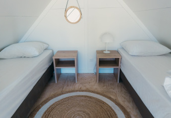 To enkelt senge i et lyst værelse med natborde og lampe på Big lodge i Holiday park De Boshoek, Holland.