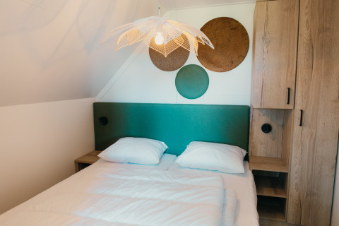 Slaapkamer in de Big lodge bij Holiday park De Boshoek, Nederland, met groen hoofdbord en moderne inrichting.