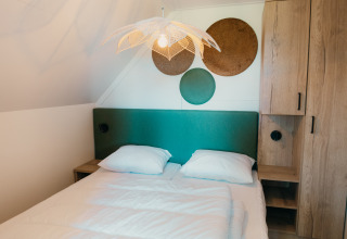 Slaapkamer in de Big lodge bij Holiday park De Boshoek, Nederland, met groen hoofdbord en moderne inrichting.