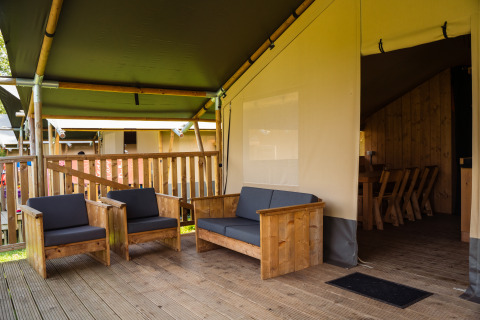 Espace détente avec meubles en bois dans tente safari avec sanitaires au Camping de Chênefleur, Belgique.