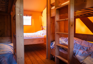 Innenaufnahme eines Safari-Zeltes mit Etagenbetten und Holzmöbeln auf Camping de Chênefleur in Belgien.