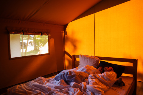 Due persone dormono in un letto accogliente all'interno di una tenda safari al Camping de Chênefleur in Belgio.