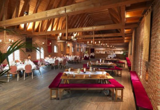 Großer Speisesaal mit Holzbalkendecke und Backsteinwänden im Expedition Archeon, Südholland, Niederlande.