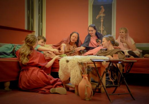 Gruppe mennesker i historisk tøj nyder et måltid i Archeon, en feriepark i Sydholland, Holland.