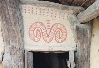 Traditional doorway decoration with red patterns in a wooden house, seen at Expedition Archeon, South Holland.