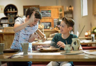 Zwei Jungen haben Spaß beim gemeinsamen Kochen in einem historischen Restaurant im Freizeitpark Archeon.