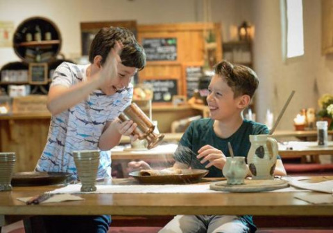 Dos niños disfrutan cocinando juntos en un restaurante histórico en Expedition Archeon, un parque en Holanda.